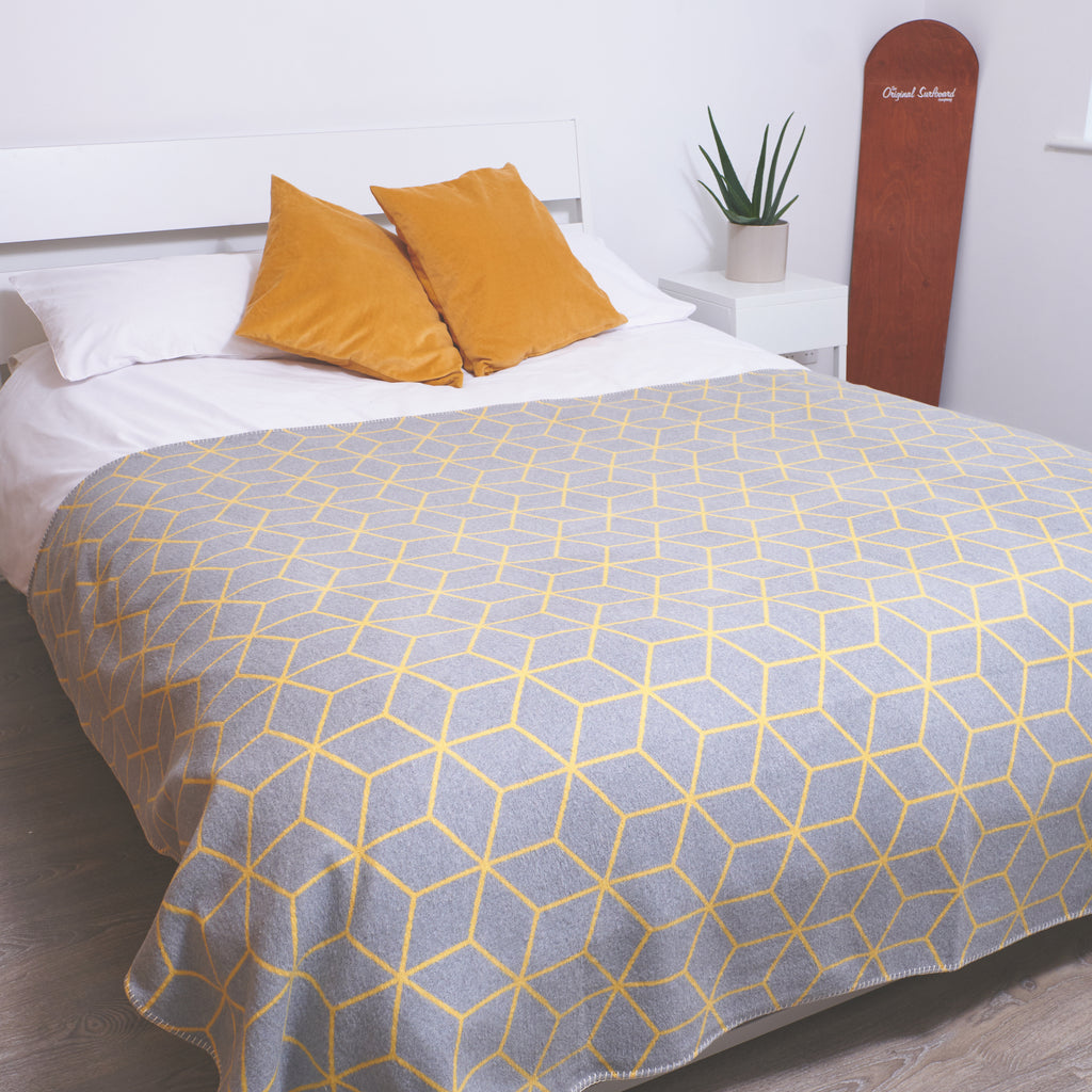 grey and yellow geometric blanket across a king size bed