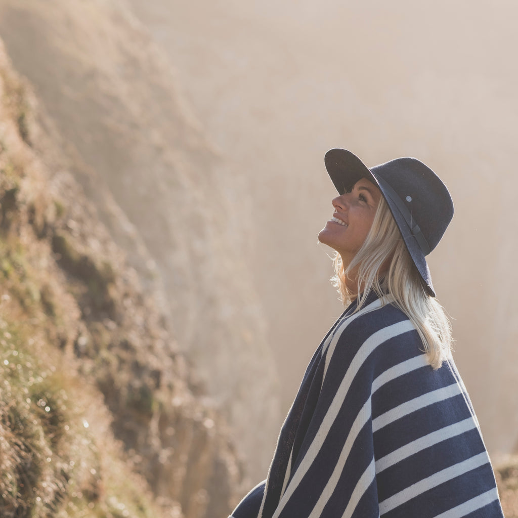 woman wrapped in a navy striped blanket on the coast